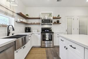 a white kitchen with a sink and a stove at Vacation Rental in Old Town Bay St Louis plus parking for RV in Bay Saint Louis
