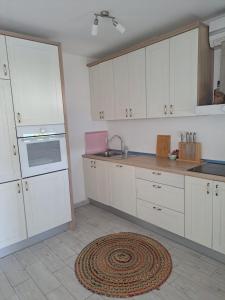 a kitchen with white cabinets and a rug on the floor at Ana in Neum