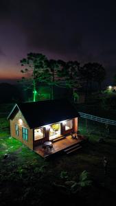 ein kleines Haus mit nachts auf einem Feld eingeschaltetem Licht in der Unterkunft Infinity Valley Cabanas in Urubici