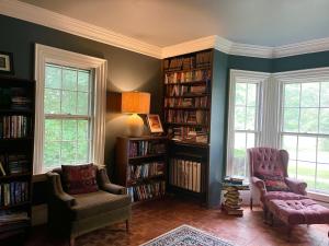 a living room with two chairs and bookshelves at Admiral Peary Inn Bed & Breakfast in Fryeburg