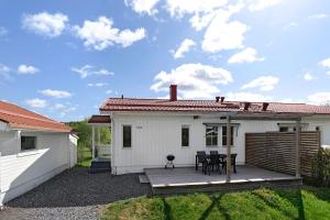 ein kleines weißes Haus mit einer Holzterrasse in der Unterkunft Guestly Homes - 4BR Villa, 6 Beds with 2 Showers in Boden