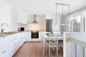 uma cozinha com armários brancos e uma mesa e cadeiras em Guestly Homes - 4BR Villa, 6 Beds with 2 Showers em Boden