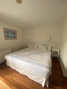 a bedroom with a large white bed with two tables at Hotel Casa Socotor in Sallent de Gállego