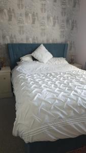 ein großes weißes Bett mit blauem Kopfteil in der Unterkunft 2 bed lodge sleeps 6 in Rhyl