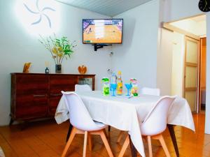 a table with white chairs and a television on a wall at LAKAY SONSON in Les Anses-dʼArlets