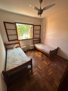 two beds in a room with a window at Casa Jardim das Colinas in São José dos Campos