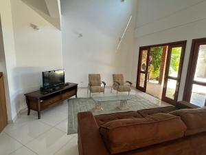 a living room with a couch and a tv at Casa Jardim das Colinas in São José dos Campos