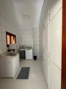 uma cozinha em azulejos brancos com uma máquina de lavar e secar roupa em Casa Jardim das Colinas em São José dos Campos