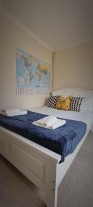 un letto con coperta blu e una mappa sul muro di Lovely 5-bed home with free parking and garden a Addington