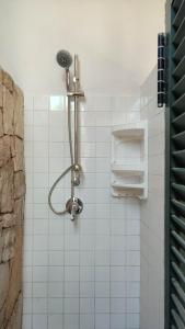 a shower in a white tiled bathroom at Porto Selvaggio Casa Zaffiro in Torre Inserraglio