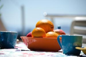 un tazón de naranjas y manzanas sobre una mesa con dos tazas en Apartments Villa Sunrise, en Trogir