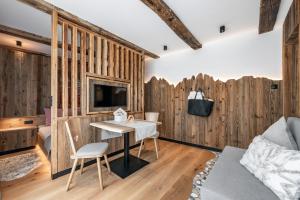 Habitación con paredes de madera, mesa y TV. en Oberkantiolhof en Villnoss