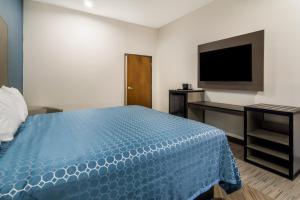 a bedroom with a blue bed and a flat screen tv at Scottish Inns- Forest Hill in Forest Hill