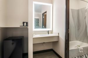 a bathroom with a sink and a mirror and a tub at Scottish Inns- Forest Hill in Forest Hill