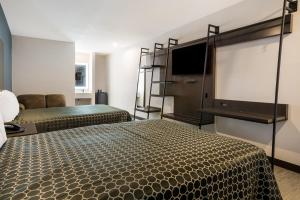 a bedroom with two beds and a flat screen tv at Scottish Inns- Forest Hill in Forest Hill