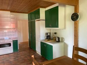 a kitchen with green cabinets and a clock on the wall at Ta det lugnt in Råda