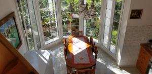 a room with a table and chairs and windows at Country House Bubullime Albania (Villa - Cottage) in Lushnjë