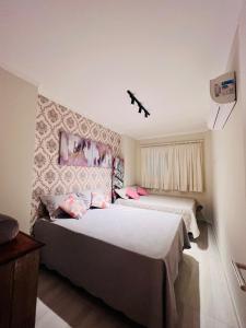 a bedroom with two beds and a wall at Ap Alto luxo em Praia Grande in Praia Grande