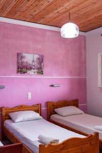 two beds in a room with a pink wall at Katerina Studios & Apartments in Sidari