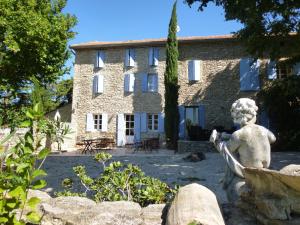 una casa de piedra con una estatua delante de ella en Le Mas des Busclats, en LʼIsle-sur-la-Sorgue