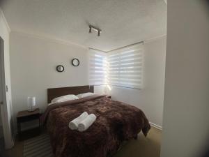 ein Schlafzimmer mit einem Bett mit zwei weißen Handtüchern darauf in der Unterkunft Apartamento boldo Curicó in Curicó