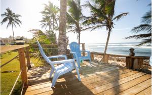 dos sillas azules sentadas en una terraza con vistas al océano en Ocean Front Villa, 2 Private Pools, BBQ, Tennis court and more!, en Vega Baja
