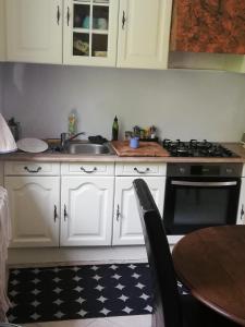una cucina con armadi bianchi, lavandino e piano cottura di VILLA DU BIEN ËTRE ad Argenton-sur-Creuse