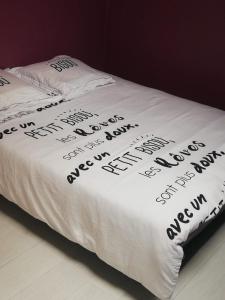 een bed met een wit dekbed met een opschrift erop bij VILLA DU BIEN ËTRE in Argenton-sur-Creuse
