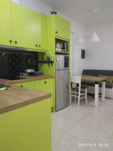 una cocina con armarios de color verde lima y una mesa en Cozy Coastal, en Perea