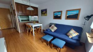 a living room with a blue couch and a table at CHECK IN CASAS Pirita in Cerler