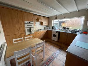 a kitchen with wooden cabinets and a table and chairs at Geneva Cottage Darlington in Darlington