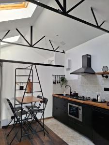 eine Küche mit schwarzen Schränken, einem Tisch und einem Herd in der Unterkunft au p'tit logis montlouisien in Montlouis-sur-Loire