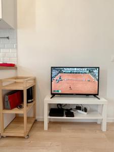een televisie op een witte tafel met een tennisspel erop bij Le nid doux - proche Paris & métro in Villejuif