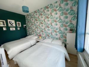 two beds in a room with a green wall at Le nid doux - proche Paris & métro in Villejuif