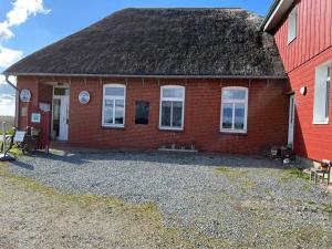 a red brick house with a black roof at Nordsee Ferienwohnung Utspann in Uelvesbüll