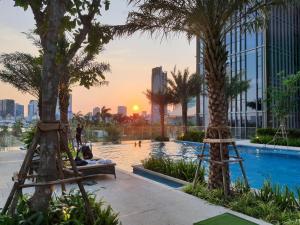 une piscine avec des palmiers et un coucher de soleil dans l'établissement Luxury Condos at Empire City, à Hô-Chi-Minh-Ville