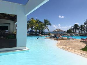 a pool at a resort with people in the water at Studios FREEBROISE in Saint-François