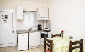 a kitchen with a table and a kitchen with white cabinets at Mani's Rose in Stoupa