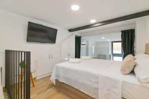 a white bedroom with a large bed and a flat screen tv at Nice Central Loft in Vilanova i la Geltrú