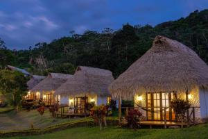 uma fileira de cabanas com telhados de palha à noite em Sauce Lodge - Laguna Azul em Sauce