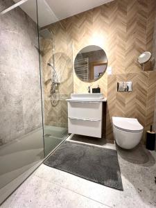 een badkamer met een toilet, een wastafel en een spiegel bij Apartament 25 Rowery, Spacery w Dolinie Baryczy - 5D Apartamenty in Milicz