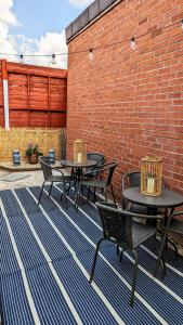 two tables and chairs on a patio with a brick wall at Huge Weekly & Monthly Savings - Free Parking - Wi-Fi & Netflix in Wolverhampton