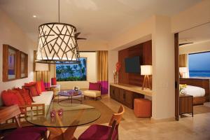 a living room with a table and a bedroom at Secrets Akumal Riviera Maya - Adults Only in Akumal