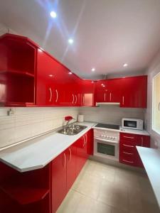 uma cozinha vermelha com electrodomésticos brancos e armários vermelhos em La Florida em Ciudad Real