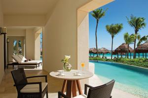 a dining room with a table and chairs next to a pool at Secrets Akumal Riviera Maya - Adults Only in Akumal