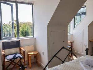 een slaapkamer met een bed en twee stoelen en ramen bij The Penthouse in Lyme Regis