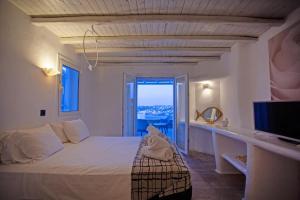 a bedroom with a large bed and a television at Nuera Villa in Mikonos
