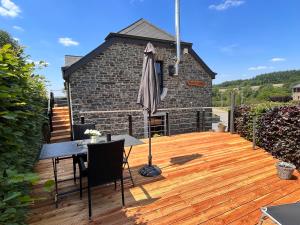 una terraza de madera con mesa y sombrilla en Gîte Libre’Air en Redu