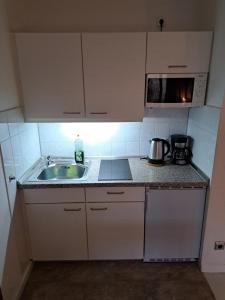 a small kitchen with a sink and a microwave at Jezza Apart Suite in Munich