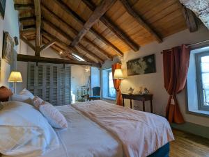 - une chambre avec un grand lit blanc et des fenêtres dans l'établissement Château de Lavaud, à Montbron